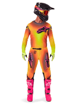 Motocross rider wearing the Alpinestars 2025 Supertech Lipan gear, featuring a vibrant Yellow and Pink gradient design, matching long-sleeved jersey, bright pink boots, lime green gloves, and a black helmet with orange goggles.