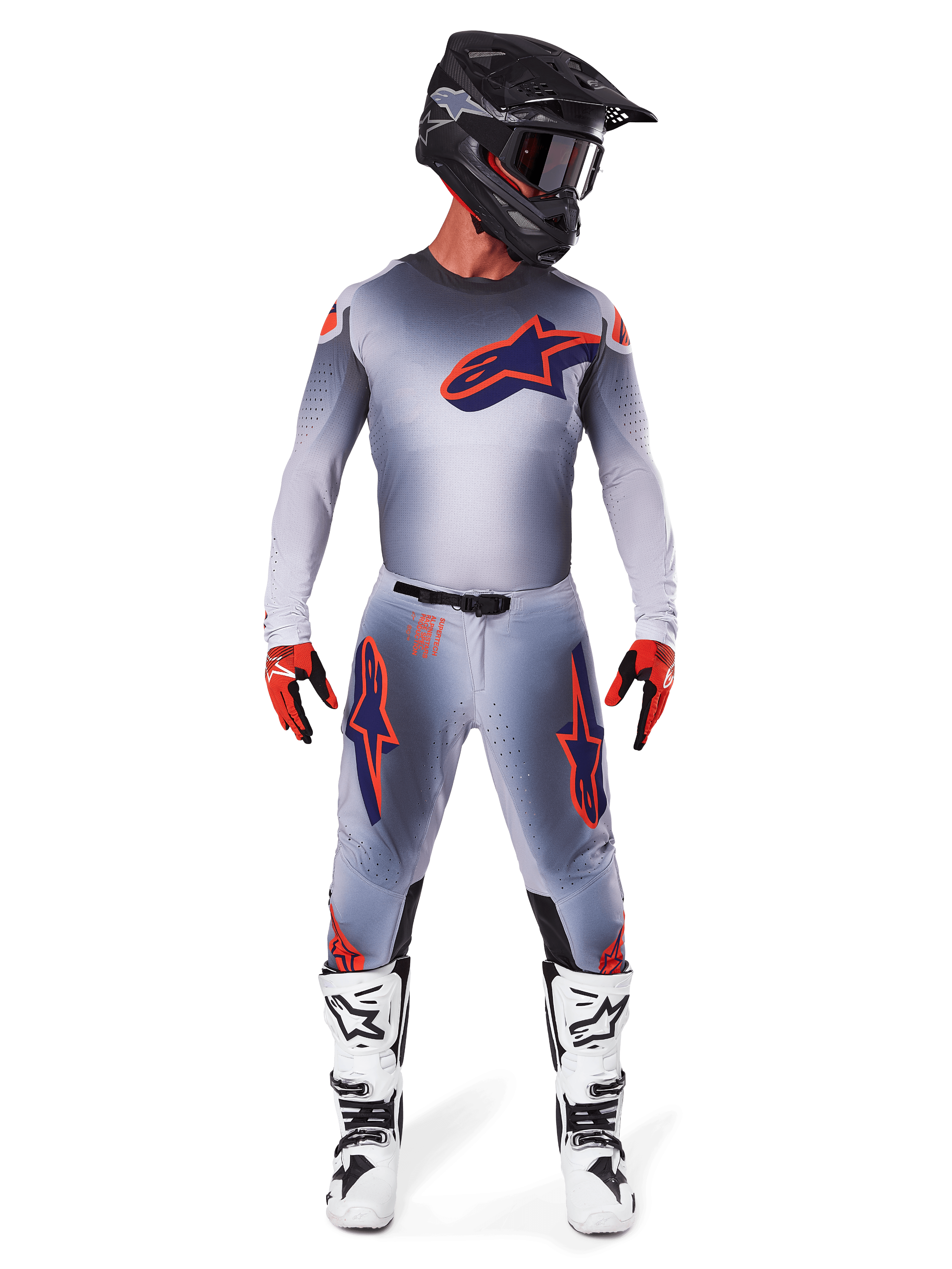Motocross rider wearing Alpinestars 2025 Supertech Lipan Pants and matching jersey in Gray Orange Fluo, featuring bold orange and navy logos, paired with a black helmet, red gloves, and white and black boots, full racing kit for off-road performance.