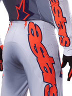 Alpinestars 2025 Supertech Lipan Pants and Jersey, Motocross Gear Set, Gray and Orange Fluo, close-up of the side and back showing large orange Alpinestars branding, performance rip-stop fabric with perforated ventilation