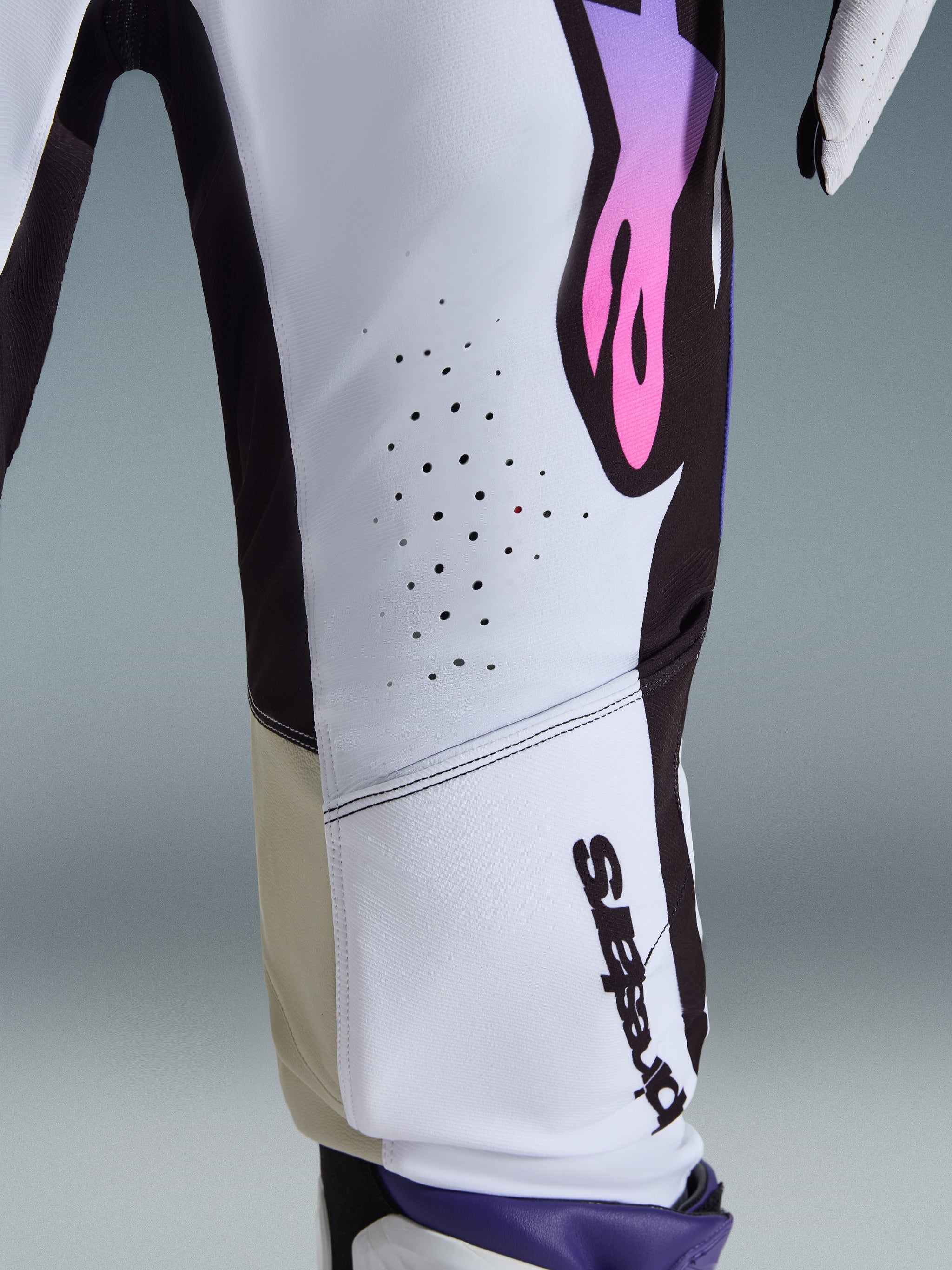 Alpinestars 2026 Supertech AFD Vista Pants, Motocross Pants, White Purple and Black, close-up showing laser-cut ventilation holes, vertical Alpinestars logo, and tan inner knee panels, performance racing gear