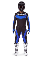 Motocross rider wearing the Alpinestars 2025 Techstar Dreem Gear Set, black jersey with blue chest panel and sleeves, matching black and blue pants, black helmet with goggles, and white boots, complete coordinated motocross outfit for off-road racing.