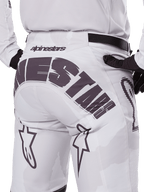 Rear view of Alpinestars 2025 Racer Hollow Pants, Motocross Pants, White and Light Camo, featuring bold black Alpinestars branding on the seat, worn with a matching jersey and black gloves