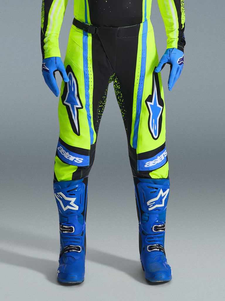 Alpinestars 2026 Techstar Nomur Pants, Motocross Pants, Yellow Fluo and Dark Navy with Blue accents, worn with matching blue gloves and boots, featuring bold Astars logos on the thighs and a performance-engineered design for off-road racing.