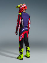 Alpinestars 2026 Fluid Grid Pants, Motocross Pants, Red Black and Purple, worn by a rider from behind with matching jersey and fluo yellow boots, featuring bold branding and ergonomic design for off-road performance.