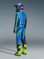 Motocross rider from a rear view wearing 2026 Alpinestars Fluid Apex Pants in Blue and Yellow Fluo, matching blue and yellow jersey and helmet, and bright neon yellow boots, coordinated racing gear for off-road performance.