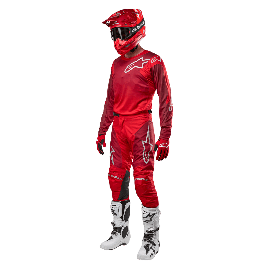 Motocross rider wearing complete racing gear, Alpinestars 2024 Racer Hoen Pants and jersey in Mars Red Burgundy, red helmet, red gloves, and white and black boots, coordinated outfit for off-road racing