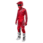 Motocross rider wearing complete racing gear, Alpinestars 2024 Racer Hoen Pants and jersey in Mars Red Burgundy, red helmet, red gloves, and white and black boots, coordinated outfit for off-road racing
