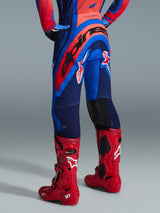 Alpinestars 2026 Supertech Vista Pants, Motocross Pants, Dark Navy Hot Coral and Cobalt, back view of rider, paired with red motocross boots, bold branding across the seat, athletic fit with stretch zones and durable rip-stop construction for professional racing