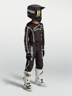 Alpinestars Youth Fluid Apex V2 Pants, black and silver motocross gear shown on-model with jersey, helmet, and white boots.