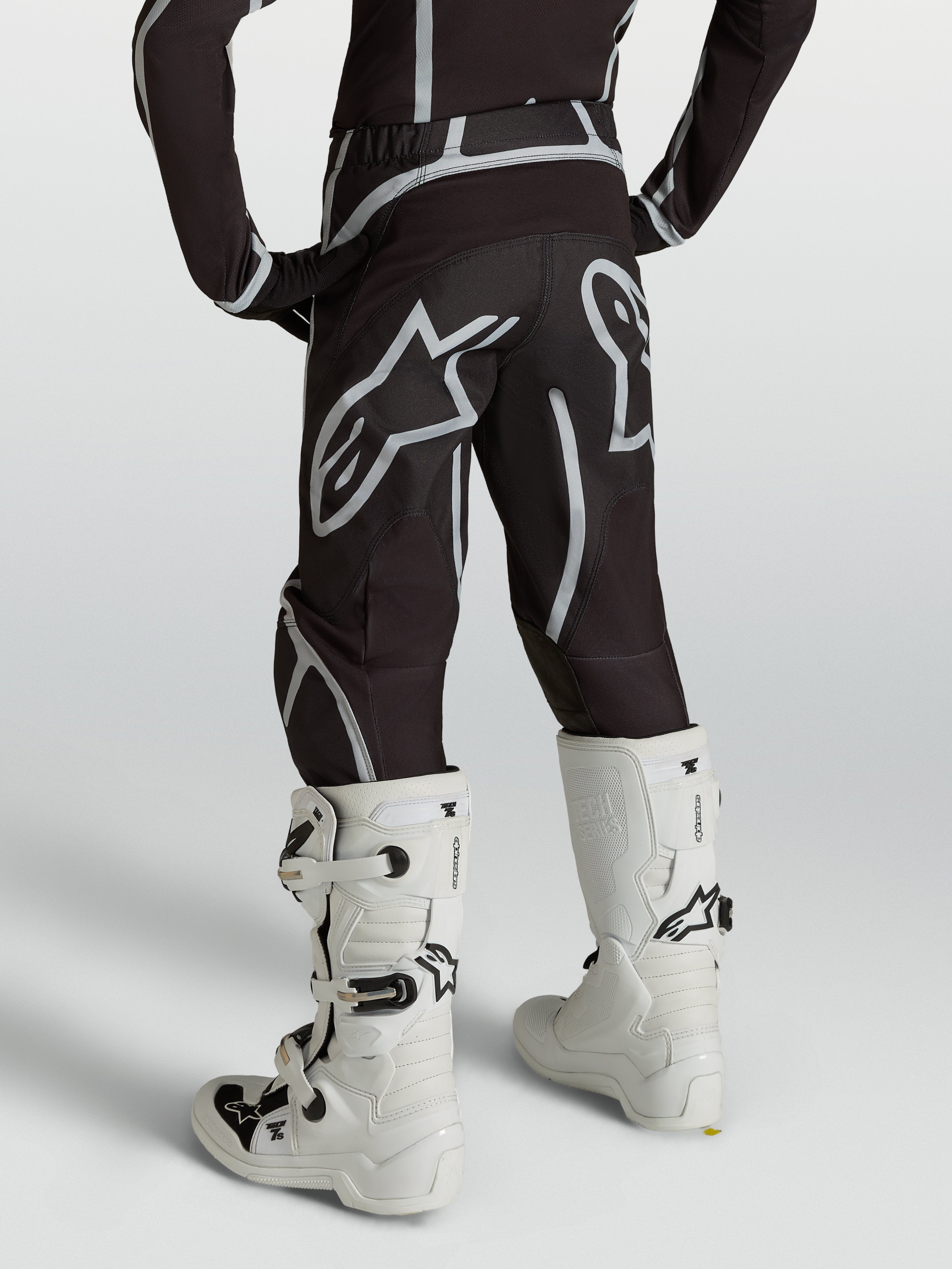 Alpinestars Youth Fluid Apex V2 Pants, Motocross Racing Gear, Youth, Black and Silver, Rear view with white boots.
