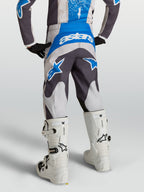 Alpinestars Youth Fluid Drag Pants in Graystone and UCLA Blue, motocross gear shown from behind on a rider with white boots.