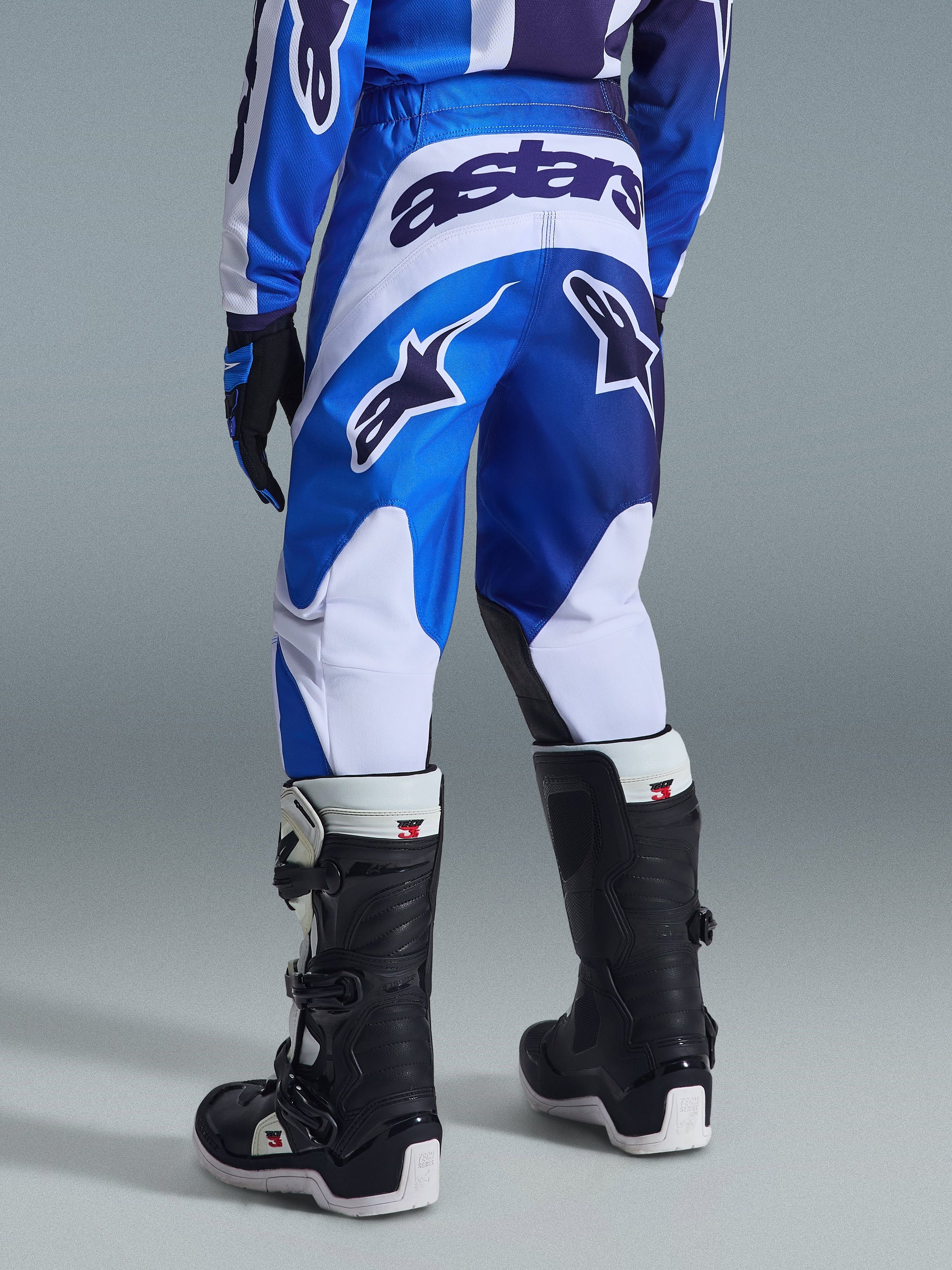 Alpinestars 2026 Youth Fluid Portl Pants, Motocross Pants, Ucla Blue and White, rear view showing bold 'astars' branding and logos, worn with black and white boots and matching jersey, durable athletic fit for young off-road riders