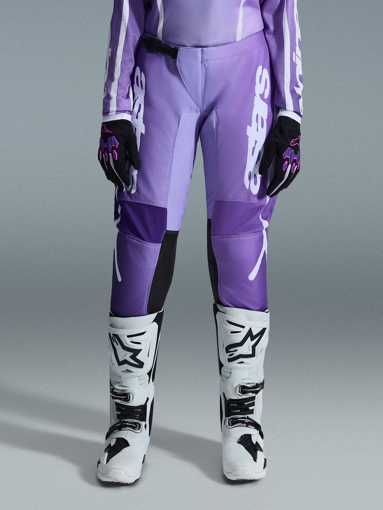 Alpinestars 2026 Woman Stella Fluid Apex Pants, Motocross Pants, Violet and White, worn with black and violet gloves and white and black boots, featuring bold white branding on the leg, ergonomic sport-fit design for off-road racing