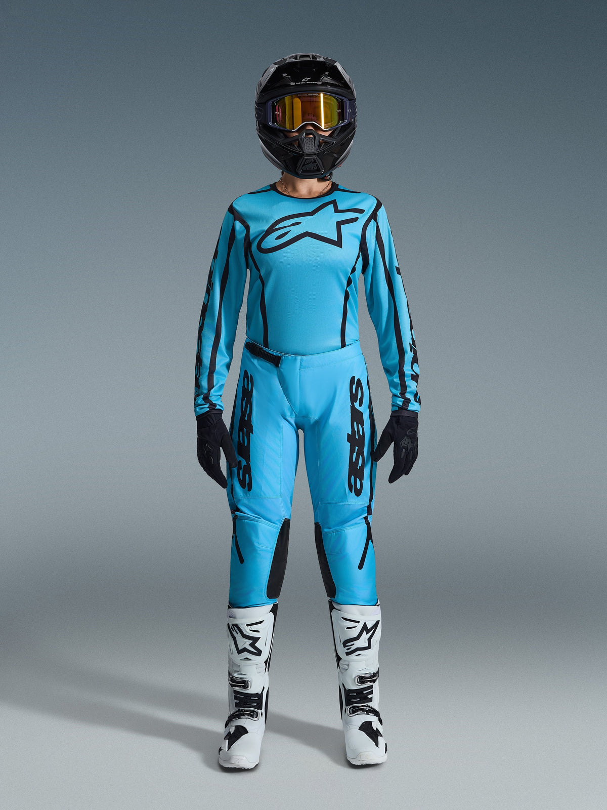 Alpinestars 2026 Stella Fluid Apex Gear Set, Women's Motocross Jersey and Pants, Blue and Black, featuring large star logo on chest, worn with black helmet, tinted goggles, and white boots with black accents, complete off-road racing outfit
