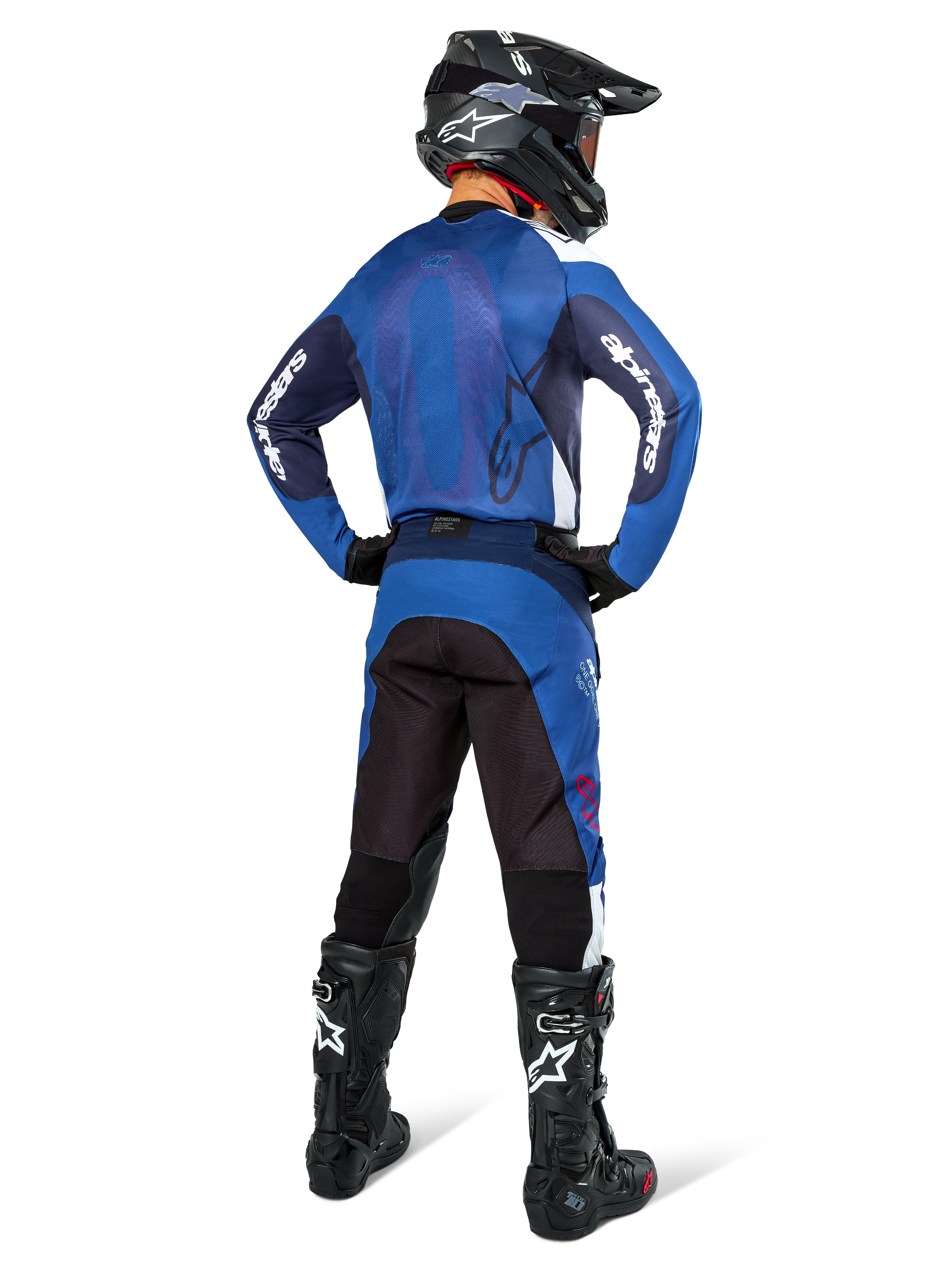 Motocross rider from the back wearing Alpinestars Pro-Dura Jersey in Navy and Bright Blue, matching blue and black pants, black motocross helmet with goggles, and black boots, showing a coordinated off-road racing outfit
