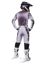 Alpinestars 2025 Supertech Maker Jersey, Motocross Jersey, Silver and Black, rear view on a rider wearing matching gear and white boots, featuring bold Alpinestars branding on sleeves and a star logo on the back, athletic race fit for professional off-road performance.