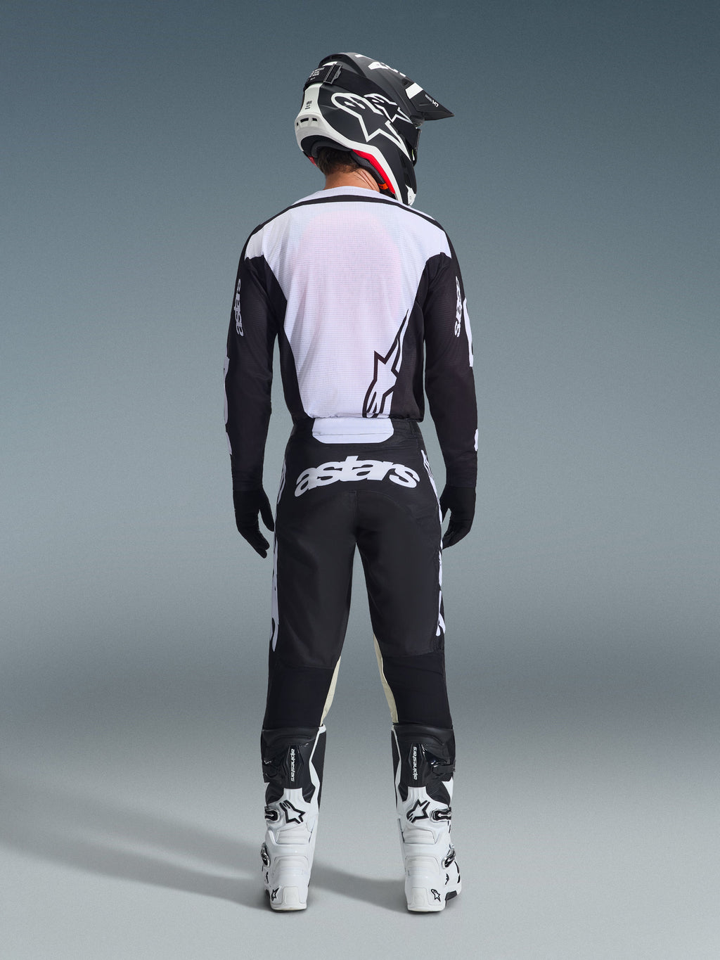 Alpinestars 2026 Racer Air Riway Gear Set, Motocross Gear, Black and White, rear view of rider wearing ventilated jersey with white mesh panels, matching pants with bold astars branding on the seat, coordinated with white and black motocross boots and helmet