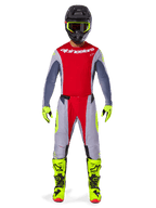 Motocross rider wearing the Alpinestars 2025 Techstar Melt Gear Set, red jersey with gray sleeves and white logo, matching gray and red pants, fluo-yellow goggles, gloves, and boots, complete motocross racing outfit for off-road performance.