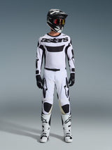 Alpinestars 2026 Racer Riway Jersey, Motocross Jersey, White and Black, worn as a complete racing kit with matching pants, black helmet with red goggles, black gloves, and white boots, featuring bold black 'astars' branding and star logos.