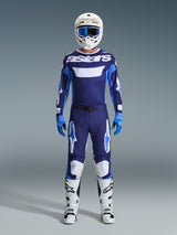 Motocross rider wearing complete racing gear, 2026 Racer Riway Jersey in UCLA Blue and White with navy panels and 'astars' chest branding, matching blue and white pants, white helmet with blue goggles, white and black boots, blue gloves, coordinated motocross racing kit.