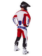 Motocross rider shown from behind wearing the Alpinestars 2025 Racer Veil Jersey and Pants in Red and White, featuring blue branding, black helmet, and white boots, complete gear set for off-road racing