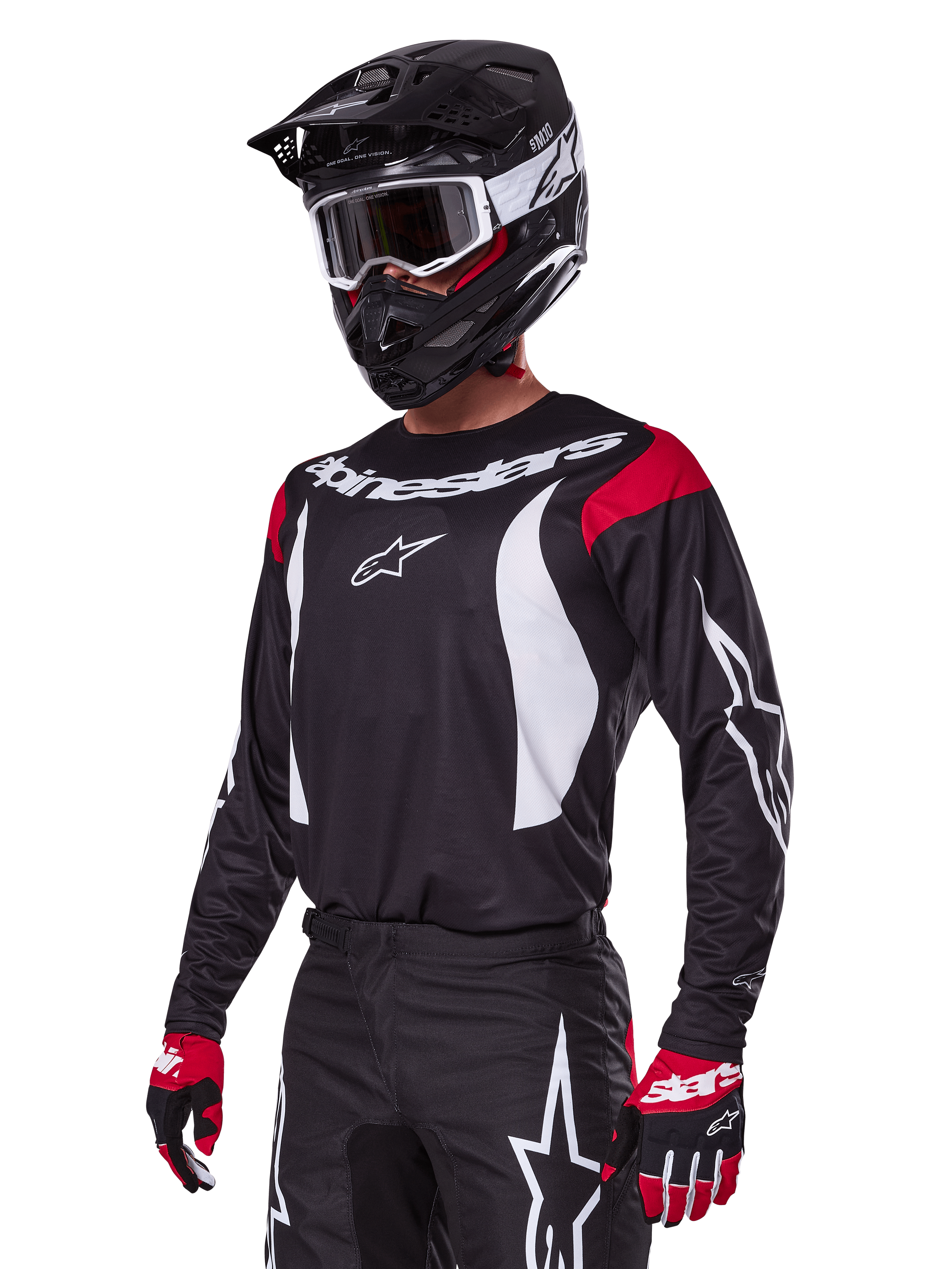 Motocross rider wearing Alpinestars 2025 Fluid Haul Gear Set, black jersey with red shoulder panels and white graphics, matching black pants with white star logos, red and black gloves, black helmet with white accents and goggles, coordinated motocross apparel.