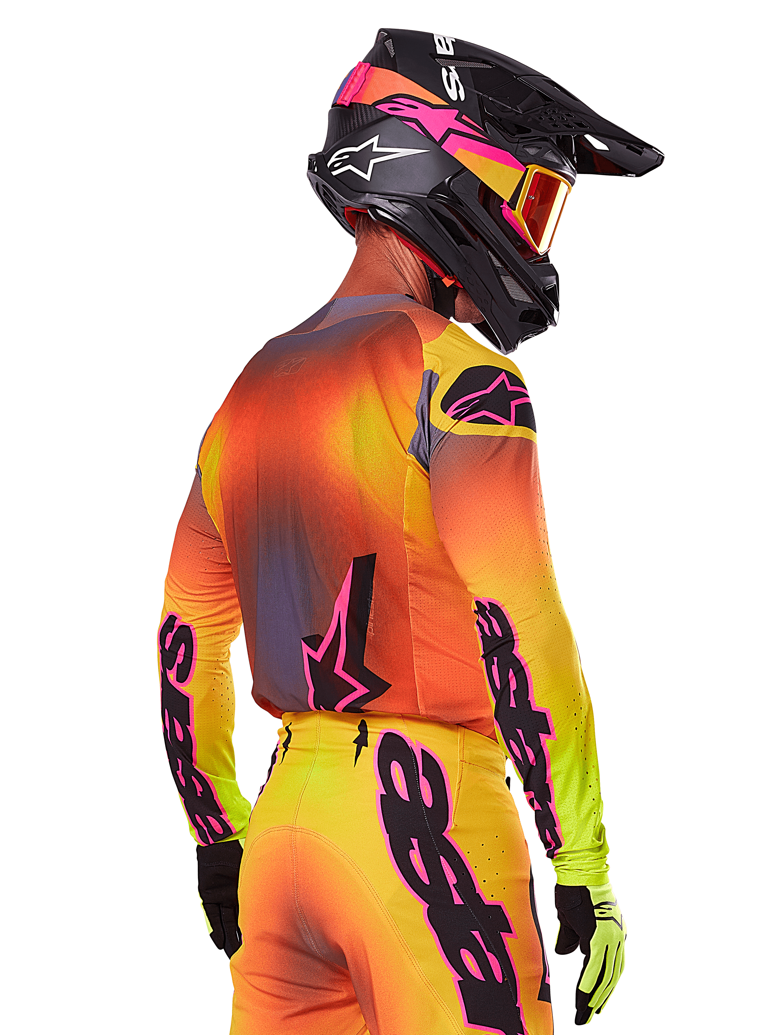 Motocross rider seen from a rear-side view wearing the Alpinestars 2025 Supertech Lipan Gear Set, featuring a yellow, orange, and red gradient with black and pink branding, black helmet with pink accents and orange goggles, professional off-road racing attire.