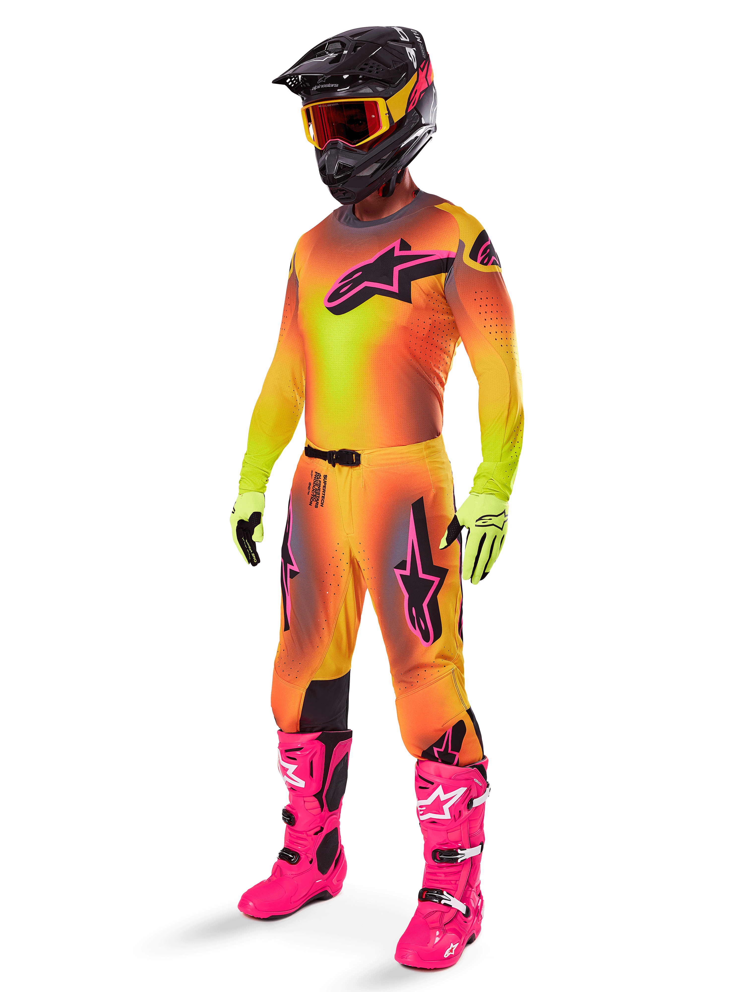 Motocross rider wearing the 2025 Alpinestars Supertech Lipan Gear Set, yellow and orange gradient jersey and pants with pink accents, black helmet with yellow-red goggles, bright yellow gloves, and vibrant pink boots, coordinated off-road racing outfit