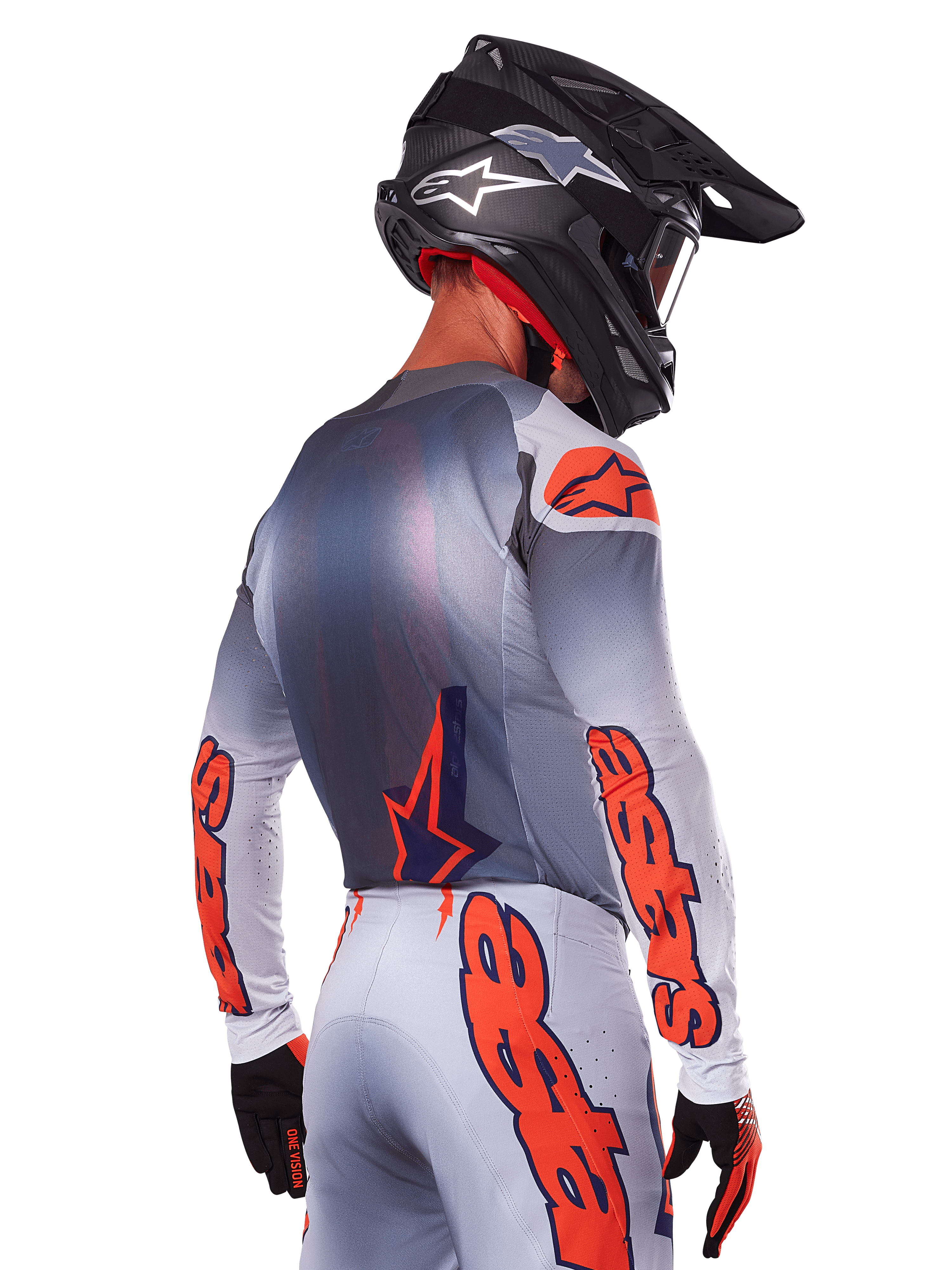 Motocross rider from the back wearing Alpinestars 2025 Supertech Lipan Jersey and Gear Set, Gray with Orange Fluo accents, featuring bold branding on back and sleeves, black helmet, and black gloves, coordinated motocross racing outfit