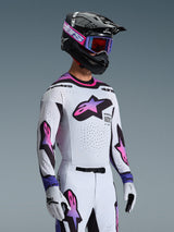 Motocross rider wearing the 2026 Supertech AFD Vista Jersey in White Purple Black, matching white and purple pants, black helmet with purple goggles and white gloves, complete professional off-road racing outfit.