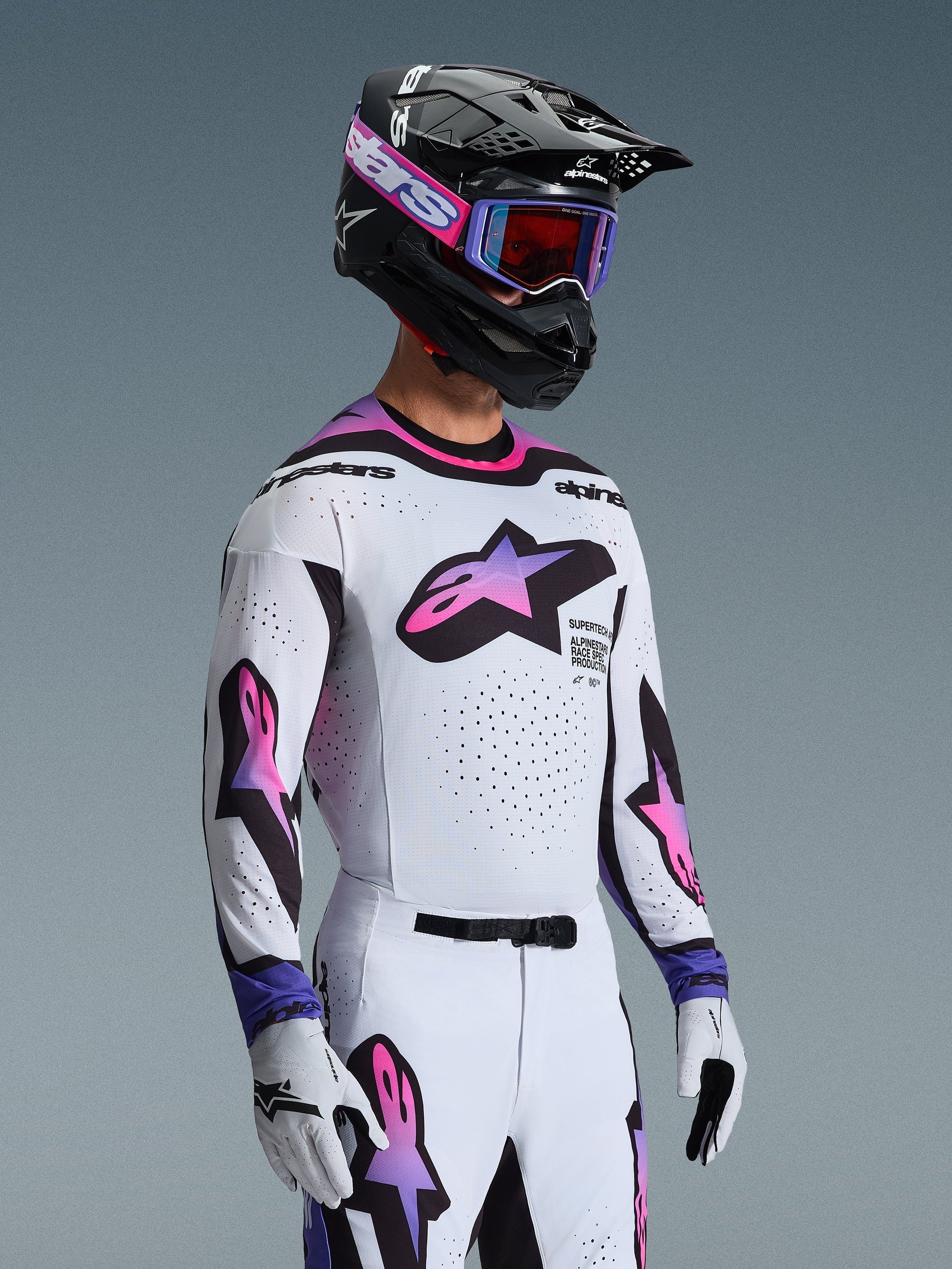 Motocross rider wearing the 2026 Supertech AFD Vista Jersey in White Purple Black, matching white and purple pants, black helmet with purple goggles and white gloves, complete professional off-road racing outfit.