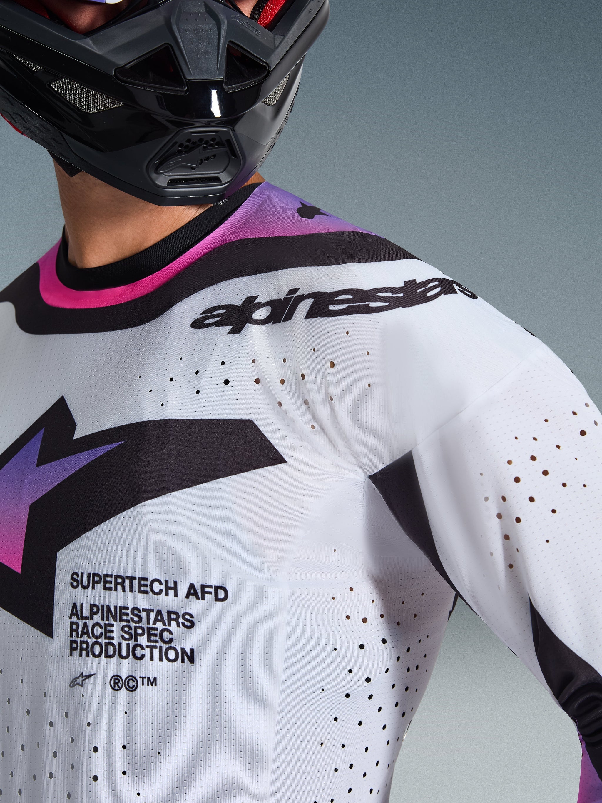 Alpinestars 2026 Supertech AFD Vista Jersey, Motocross Jersey, White Purple and Black, close-up view showing laser-cut perforations and race spec branding, worn with a black helmet, professional off-road racing gear