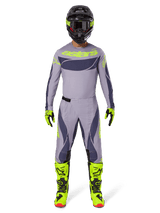 Motocross rider wearing full racing gear, 2025 Techstar Dreem Jersey in Gray and Dark Gray with neon yellow branding, matching gray and dark gray pants, neon yellow and black boots, black helmet with neon accents, coordinated outfit for professional motocross
