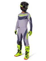 Motocross rider wearing the 2025 Techstar Dreem Jersey in gray and dark gray with neon yellow accents, complete racing gear set including matching gray pants, neon yellow boots and gloves, and a black helmet, coordinated off-road performance outfit