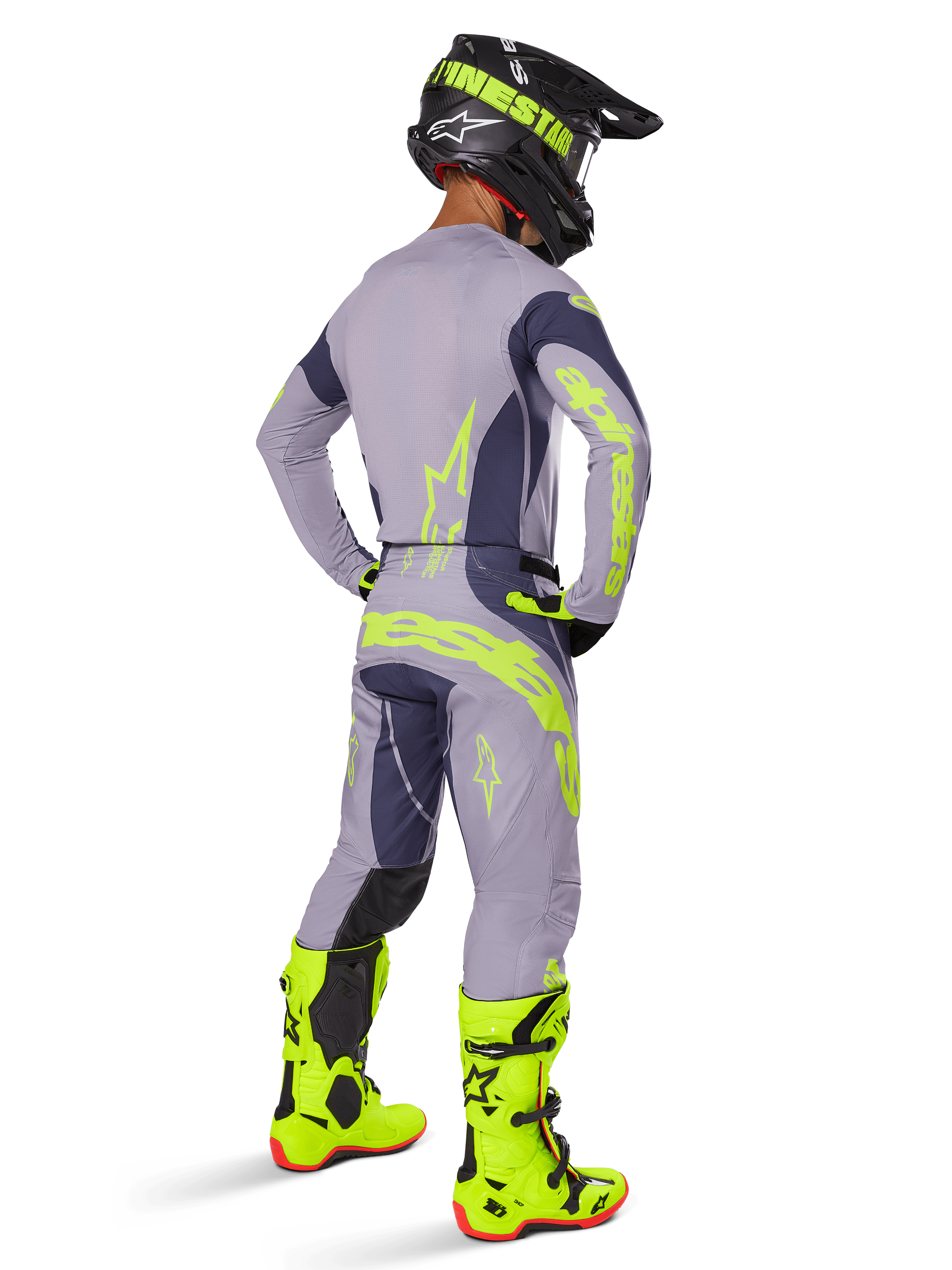 Motocross rider from a rear view wearing the Alpinestars 2025 Techstar Dreem Gear Set, Gray and Dark Gray with fluorescent yellow branding, matching jersey and pants, black helmet with yellow accents, and bright fluorescent yellow boots, coordinated professional motocross racing outfit.