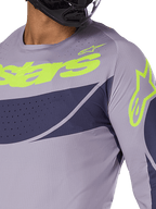 Alpinestars 2025 Techstar Dreem Jersey, Motocross Jersey, Gray and Navy Blue with Bright Lime Green logo, close-up of rider wearing black helmet, featuring laser-cut perforations for ventilation