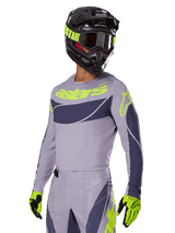 Motocross rider wearing the Alpinestars 2025 Techstar Dreem Jersey in Gray and Dark Gray, featuring a neon yellow 'astars' logo on the chest, paired with a matching helmet, goggles, and gloves for a coordinated off-road racing look