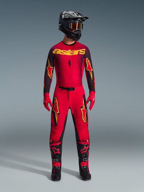 Alpinestars 2026 Supertech Scenz Gear Set, complete motocross racing outfit in red and black with yellow graphics, featuring a pro-level jersey and matching pants, worn with a black helmet, red gloves, and black racing boots, premium performance gear for off-road competition