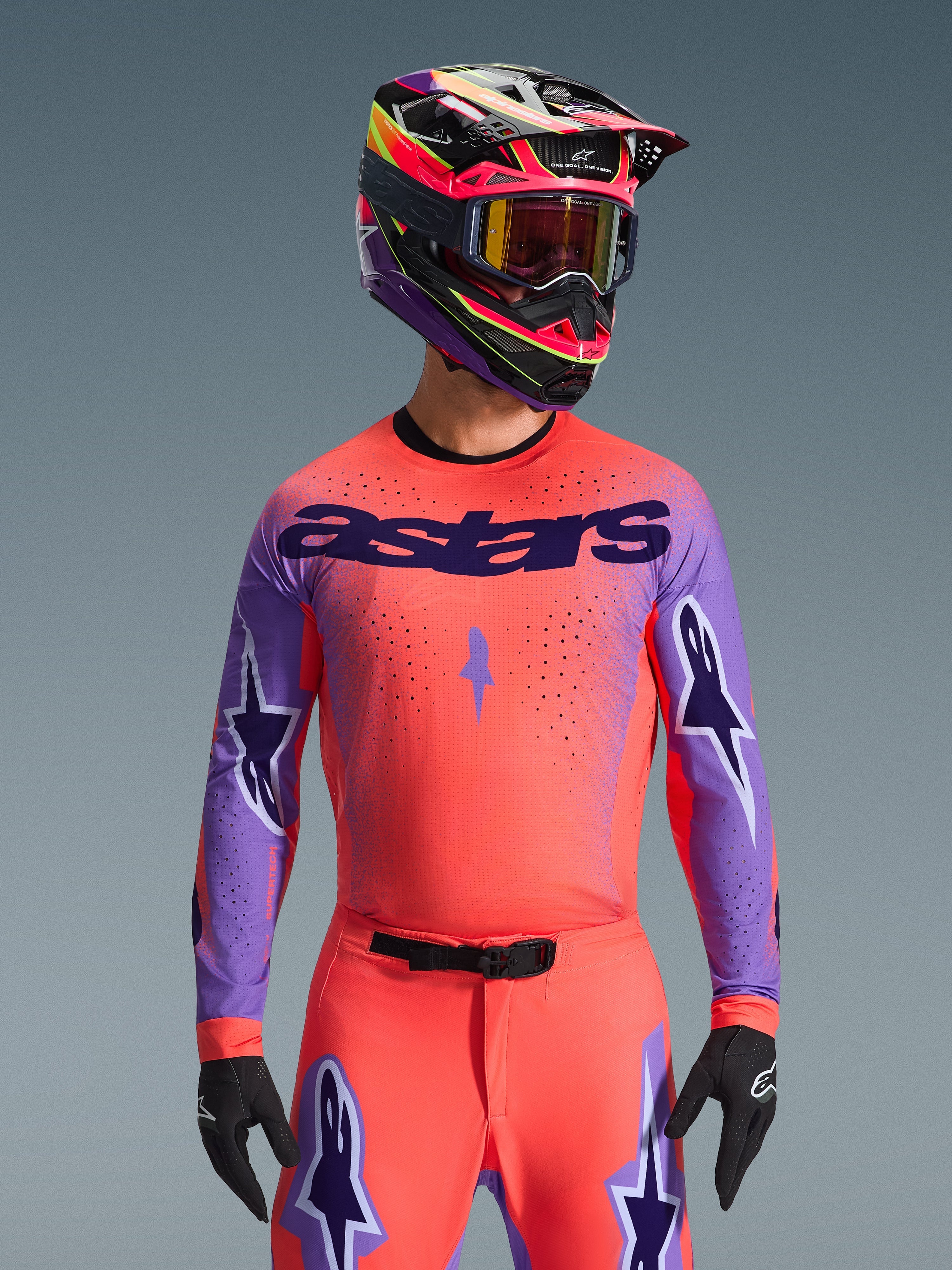 2026 Supertech Scenz Jersey, Motocross Racing Jersey, Hot Coral and Purple, featuring large 'astars' branding and sleeve star designs, worn with matching pants and a multi-colored helmet, high-performance off-road gear