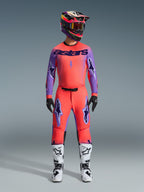2026 Supertech Scenz Gear Set, Alpinestars Motocross Racing Outfit, vibrant red-orange and purple, jersey with black 'astars' branding, matching pants with purple star logos, colorful racing helmet, and white boots, professional off-road performance kit