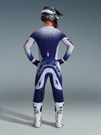 Alpinestars 2026 Supertech Scenz Gear Set, back view of a motocross rider in blue and white racing jersey and pants, stippled gradient effect, worn with white motocross boots and black helmet, pro-level dirt riding gear
