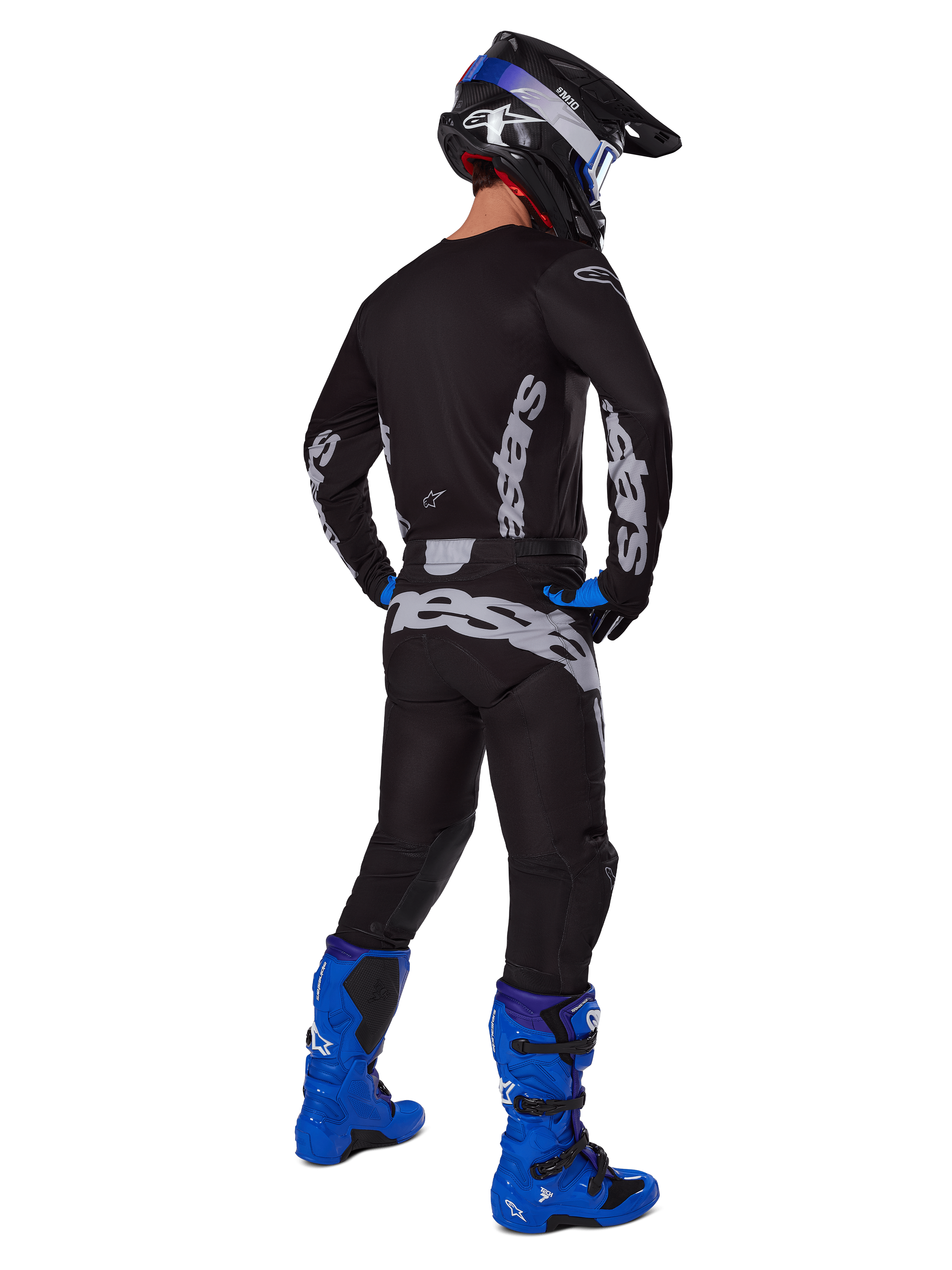 Motocross rider from a rear view wearing the Alpinestars 2025 Racer Graphite Gear Set, Black and Gray jersey and pants with gray branding, paired with bright blue motocross boots, a black and blue helmet, and blue gloves, complete performance off-road outfit.