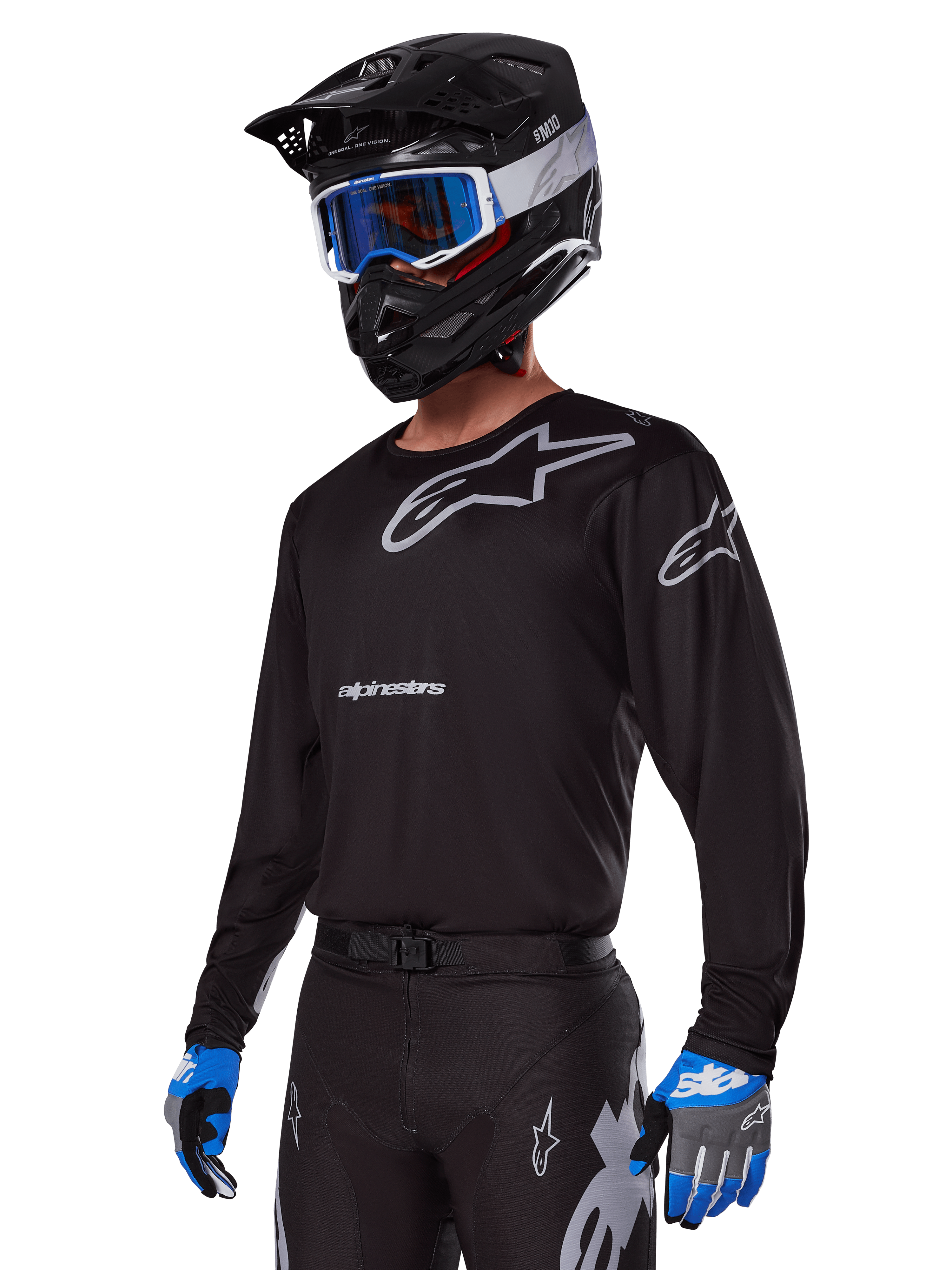 Motocross rider wearing Alpinestars 2025 Racer Graphite Gear Set, Black jersey with grey Alpinestars logos, matching black pants with grey accents, black helmet with blue and white goggles, blue and grey gloves, sleek technical outfit for off-road racing