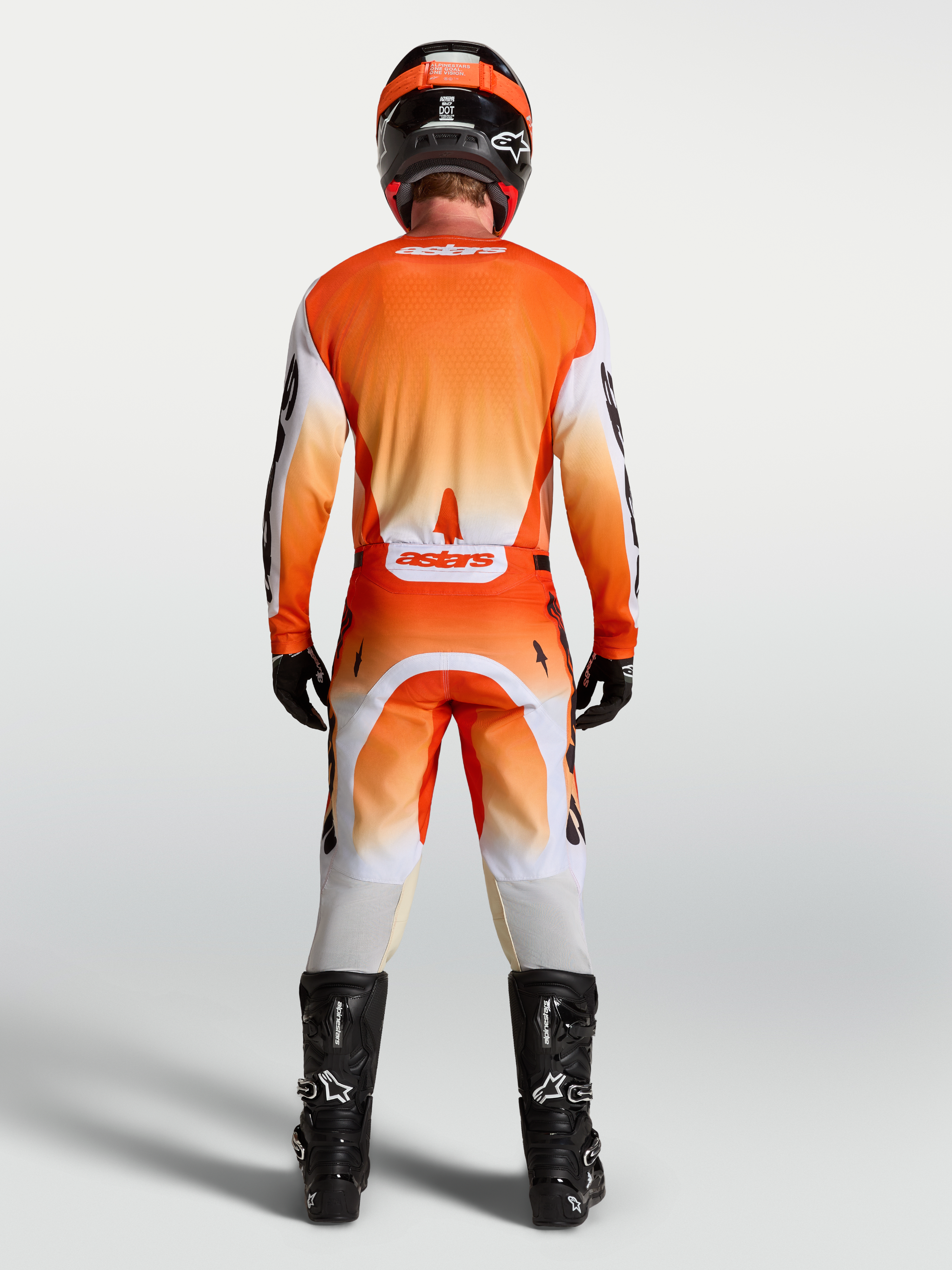 Alpinestars 2027 Racer Amber Gear Set, orange and red motocross jersey and pants, back view on rider with black boots.