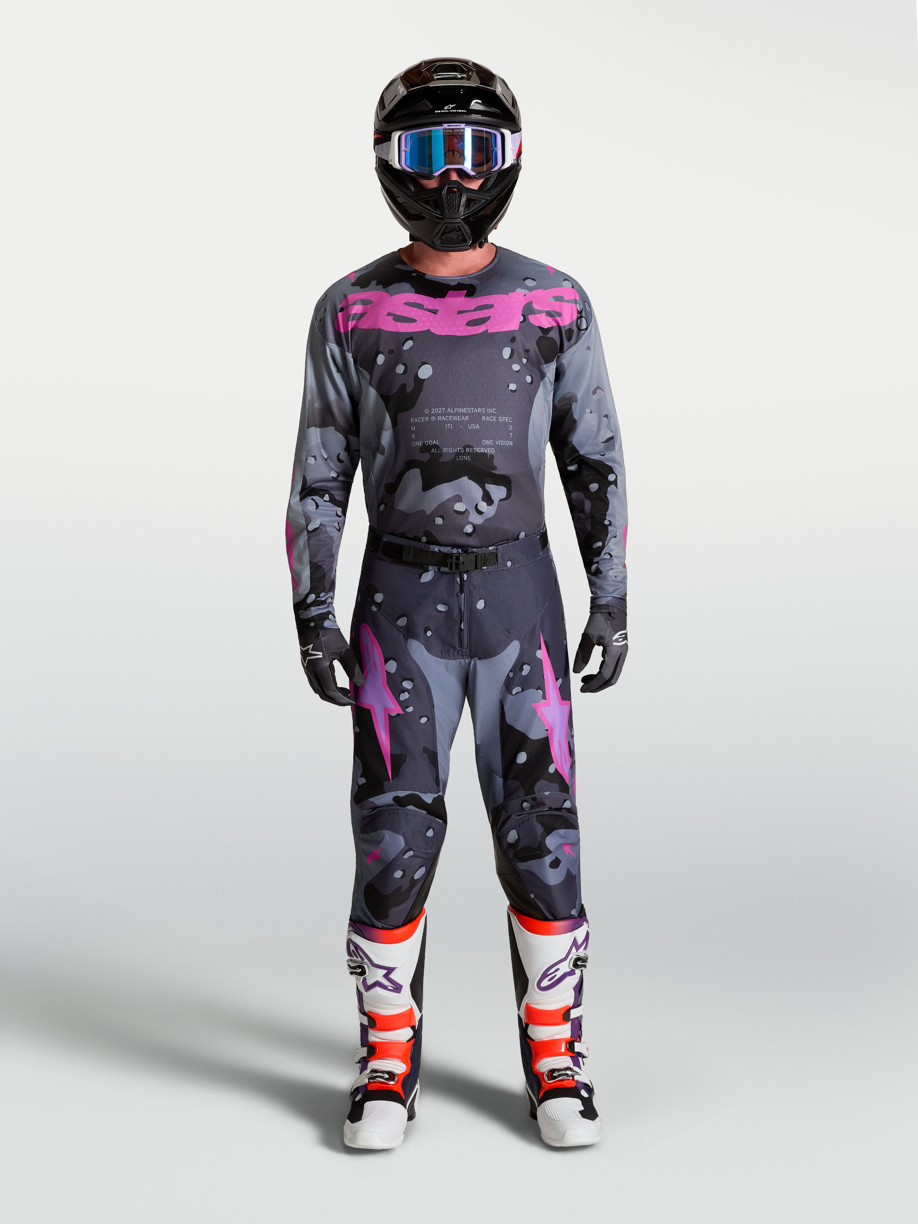 Alpinestars Racer Lone Jersey, men's gray camo and purple motocross gear set with helmet and protective boots.