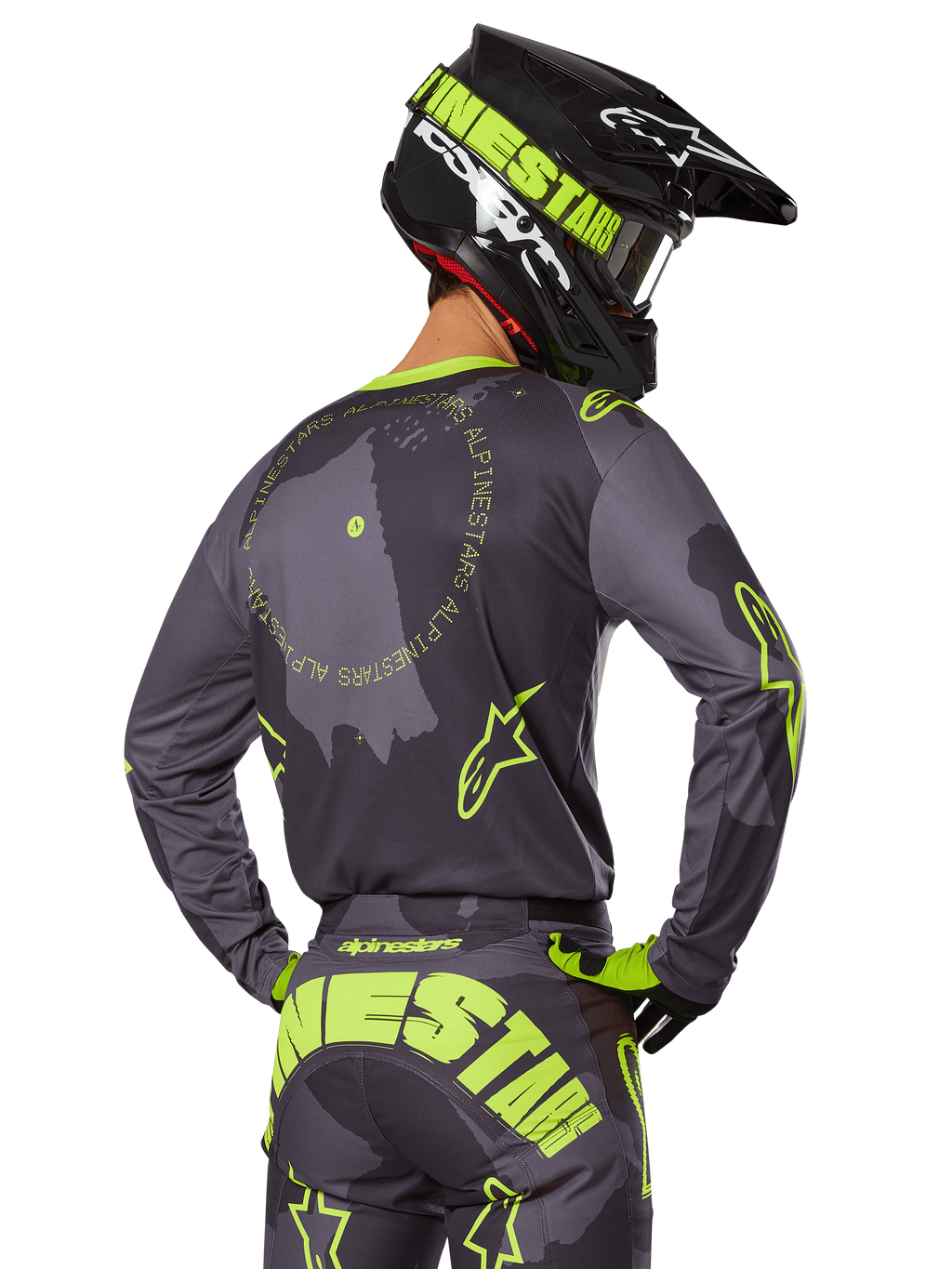 Motocross rider seen from behind wearing the 2025 Racer Hollow Gear Set, Gray jersey with fluorescent yellow circular text and star logos, matching gray and yellow pants with bold branding across the seat, black and lime green helmet, coordinated outfit for off-road racing