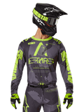 Alpinestars 2025 Racer Hollow Jersey, Motocross Racing Jersey, Dark Camo and Neon Yellow, worn with matching pants, black and yellow helmet with goggles, and black gloves, featuring Alpinestars branding and camouflage design