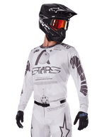 Alpinestars 2025 Racer Hollow Gear Set, Motocross Jersey and Pants, White with black and grey graphics, featuring 'ASTARS' branding and hollow globe designs, worn with a black helmet, red mirrored goggles, and black gloves, designed for off-road performance