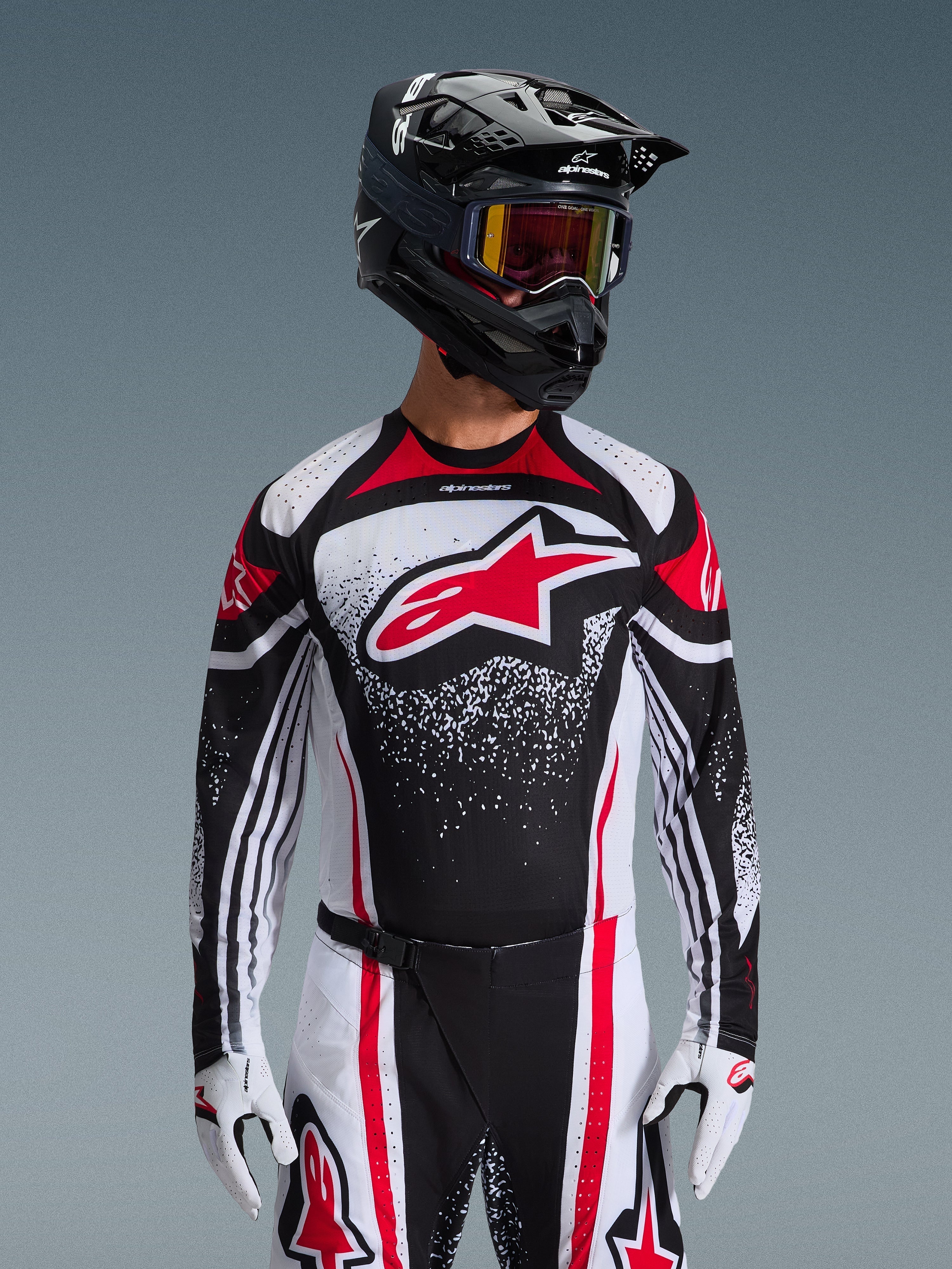 Alpinestars 2026 Techstar Nomur Jersey, Motocross Jersey, Black White and Red, worn by a rider with matching pants, black helmet, and white gloves, featuring a large red Astars logo and speckled graphic design, athletic race fit for off-road competition