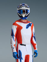 Alpinestars 2026 Fluid Grid Jersey, Motocross Jersey in Orange UCLA Blue, worn by a rider with matching white and orange pants, blue and white helmet, blue goggles, and blue gloves, complete off-road racing gear set